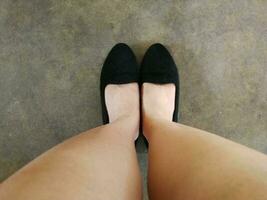 pies de una mujer con zapatos negros de pie en el suelo. vista desde mirar hacia abajo. foto