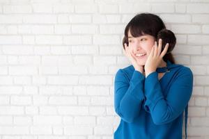 retrato de una hermosa joven asiática disfrutando y feliz de pie sobre un fondo de ladrillo de pared gris con textura de cemento, la chica es una sonriente y alegre sobre hormigón. foto