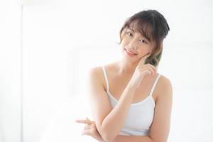 Portrait of beautiful young asian woman smile while wake up healthy and wellness with sunrise at morning in the bedroom, asia girl skin care with happy with fresh, lifestyle and relax concept. photo
