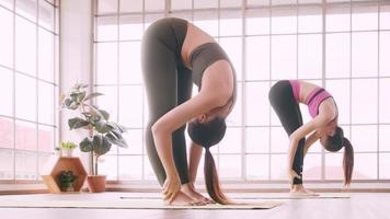dos chicas asiáticas haciendo ejercicios de yoga en casa. foto