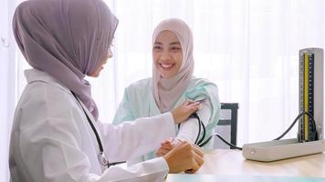 Muslim female doctor checking up patient's blood pressure at hospital room. photo