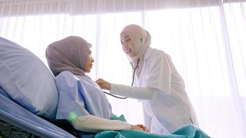 Muslim female doctor checking up patient's health at hospital room. photo