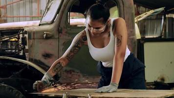 Attractive young woman mechanical worker repairing a vintage car in old garage. photo