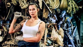 Attractive young woman mechanical worker repairing a vintage car in old garage. photo