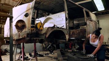 Attractive young woman mechanical worker repairing a vintage car in old garage. photo