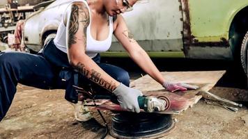 Attractive young woman mechanical worker repairing a vintage car in old garage. photo