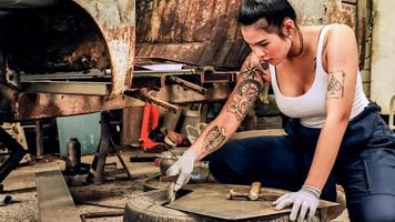 Attractive young woman mechanical worker repairing a vintage car in old garage. photo