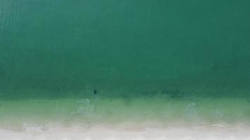 hermosas olas del mar y playa de arena blanca en la isla tropical. suaves olas de océano azul en el fondo de la playa de arena desde la vista superior de los drones. concepto de relajación y viajes de vacaciones. video