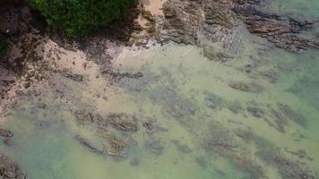 bela vista aérea do litoral da ilha na baía de phang nga do mar de andaman, cercada por pinheiros e pequenas rochas. video