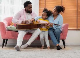 Happy african family playing guitar and singing together at home photo