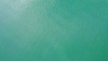 vista aérea de um drone do mar de andaman. fundo das ondas do mar com a luz do sol refletida na superfície da água. fundo do mar azul no mar tropical. video