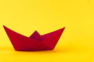 Red paper boat on a yellow background. Copy space. photo