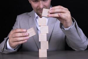 A businessman builds a pyramid of wooden cubes to write a seven-letter word. Copy space photo