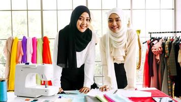 Happy muslim women working together at the clothing office. photo