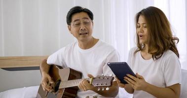 Happy asian lover playing guitar and singing songs together in a room. photo