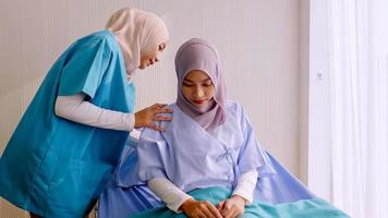 Muslim female physiotherapist taking care of patient at hospital room. photo