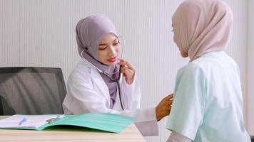 Muslim female doctor checking up patient's health at hospital room. photo