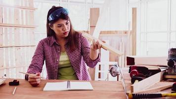 Female carpenter holding and checking piece of board at site. photo