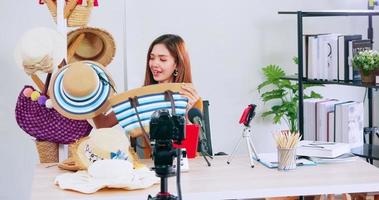 Young asian girl selling fashion hats and bags on social media by streaming live from her home. photo