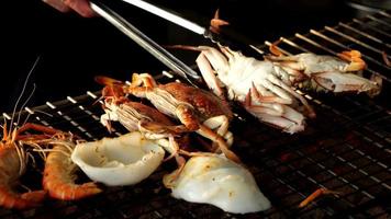 4K Slow motion video of hand grilling seafood with crab, shrimp and squid, the famous street food of Thailand.