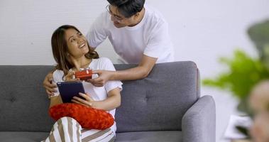 asain hombre dando una caja de regalo roja a una mujer feliz. foto