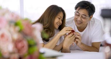 Happy asian couple holding red heart decorations together in a bedroom. photo