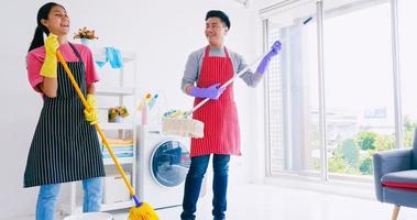 marido y mujer divirtiéndose mientras limpian su habitación. feliz pareja asiática pasando tiempo juntos en casa. foto