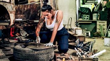 atractiva joven trabajadora mecánica reparando un auto antiguo en un viejo garaje. foto