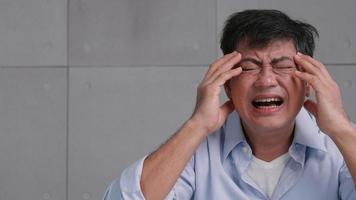 anciano asiático con dolor de cabeza por migraña. el hombre se siente estresado y preocupado por los problemas de salud. foto