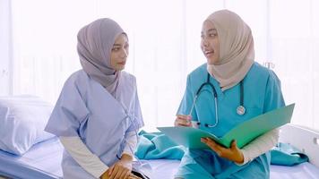 Muslim female doctor talking with patient at hospital room. photo