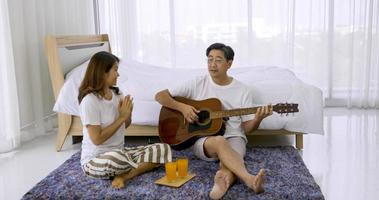 Happy asian lover playing guitar and singing songs together in a bedroom. photo