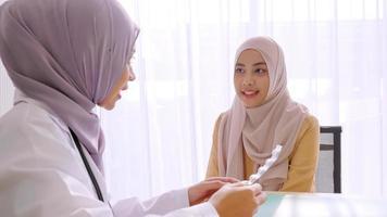 Muslim female doctor giving pill to patient at hospital room. photo