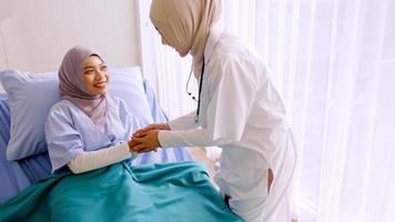 Muslim female doctor talking with patient at hospital room. photo