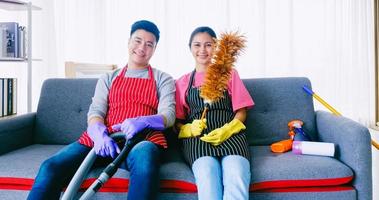 Happy husband and wife sitting on sofa after cleaning room together. photo