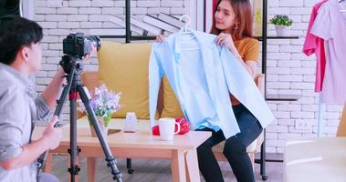Young asian couple selling fashion clothes online by live streaming with digital camera. photo