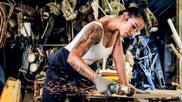 Attractive young woman mechanical worker repairing a vintage car in old garage. photo