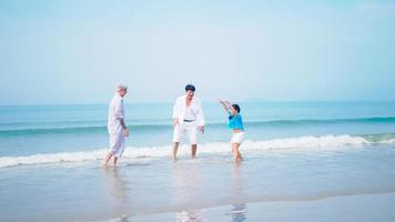 Grandfather and grandmother are playing with their little granddaughter on the beach. photo