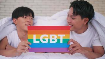 Happy gay Asian couple showing their love with rainbow flag. photo