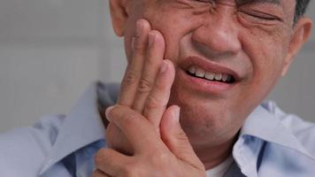 Asian senior man suffering from toothache. photo