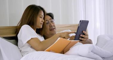 Happy asian couple watching tablet together in a bedroom. photo