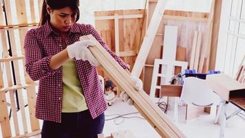 Female carpenter holding and comparing size of pieces of boards at site. photo