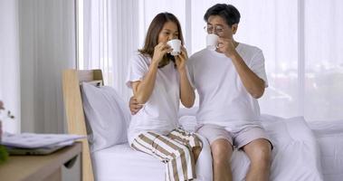 Happy asian couple drinking coffee together in bedroom. photo