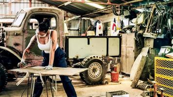 atractiva joven trabajadora mecánica reparando un auto antiguo en un viejo garaje. foto