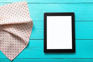 Electronic device with place for text and tablecloth in polka dots on blue wooden background. Top view and copy space. photo