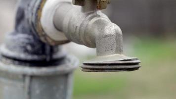 Wasserhahn auf dem Hintergrund der Natur. Das Öffnen oder Schließen eines Wasserhahns, um Wasser zu sparen, weist auf ein Problem mit Wassermangel hin. Rustikaler Brunnen mit Tageslicht. selektiver Fokus mit unscharfem Hintergrund. video