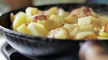asar papas frescas en una sartén de hierro fundido con aceite de girasol. una vista de una estufa con una sartén llena de papas fritas doradas en una cocina real. comida cocinada en una sartén casera.