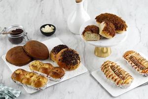 varios panes dulces y salados para el concepto de panadería, sobre mesa blanca. foto