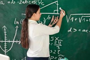 Girl writes mathematical examples on the school board. solves a geometry problem. photo