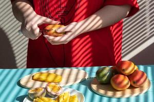 manos femeninas cortan mango y fruta de la pasión, desayuno de frutas foto