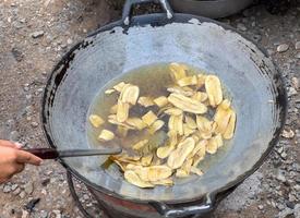 The banana slices are fried in hot vegetable oil for making banana chips. photo